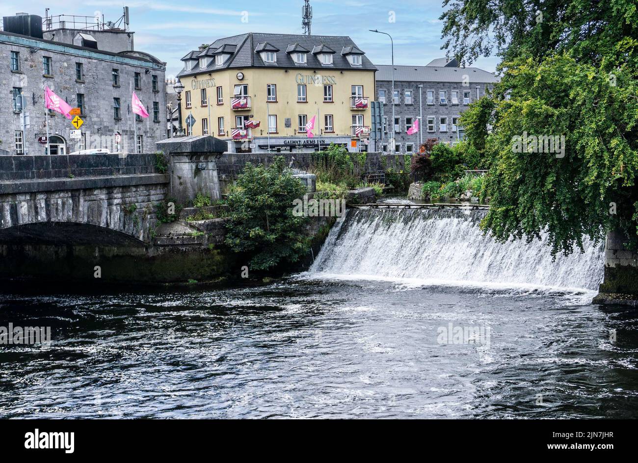 Der Corrib River in Galway City mit einem Wasserfall auf der rechten Seite und dem Galway Arms Inn im Hintergrund. Stockfoto
