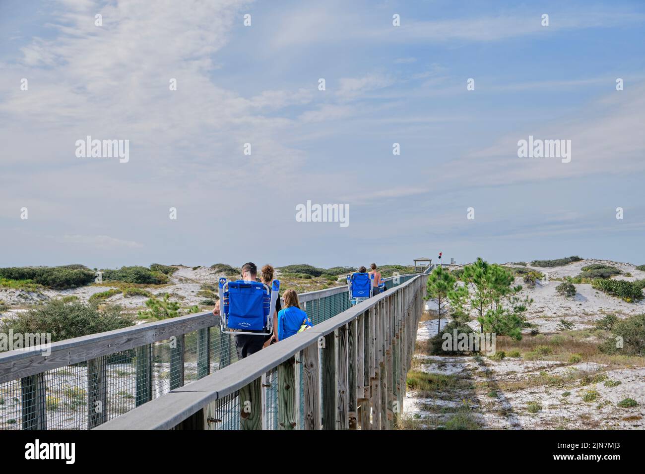 Familie im Urlaub Gehen Sie auf einem Holzsteg zum Strand im Deer Lake State Park, im Florida Panhandle an der Florida Gulf Coast, USA. Stockfoto