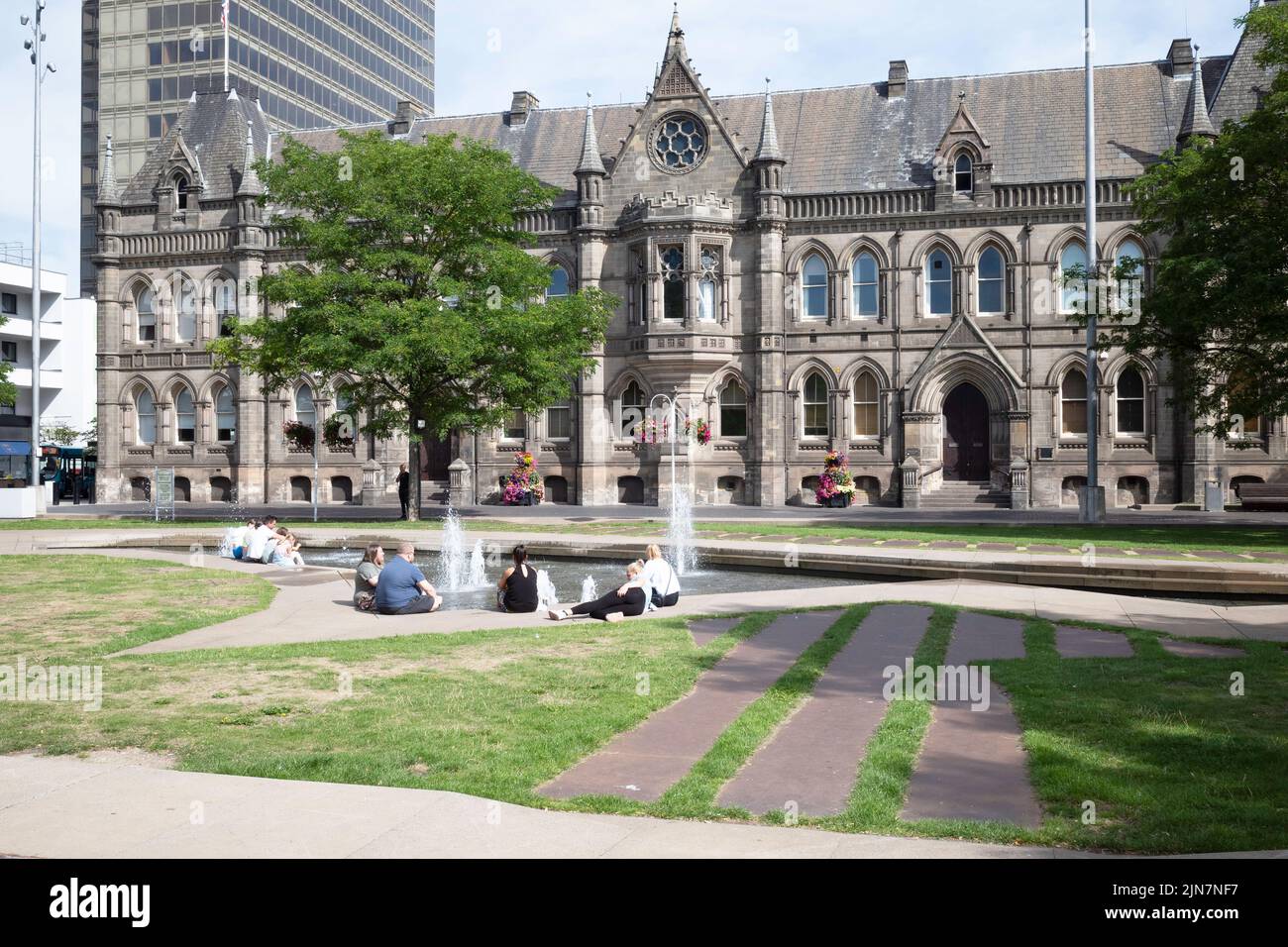 Menschen, die sich in der Sommersonne an den Springbrunnen am Rathaus am Middlesbrough Centre Square entspannen Stockfoto