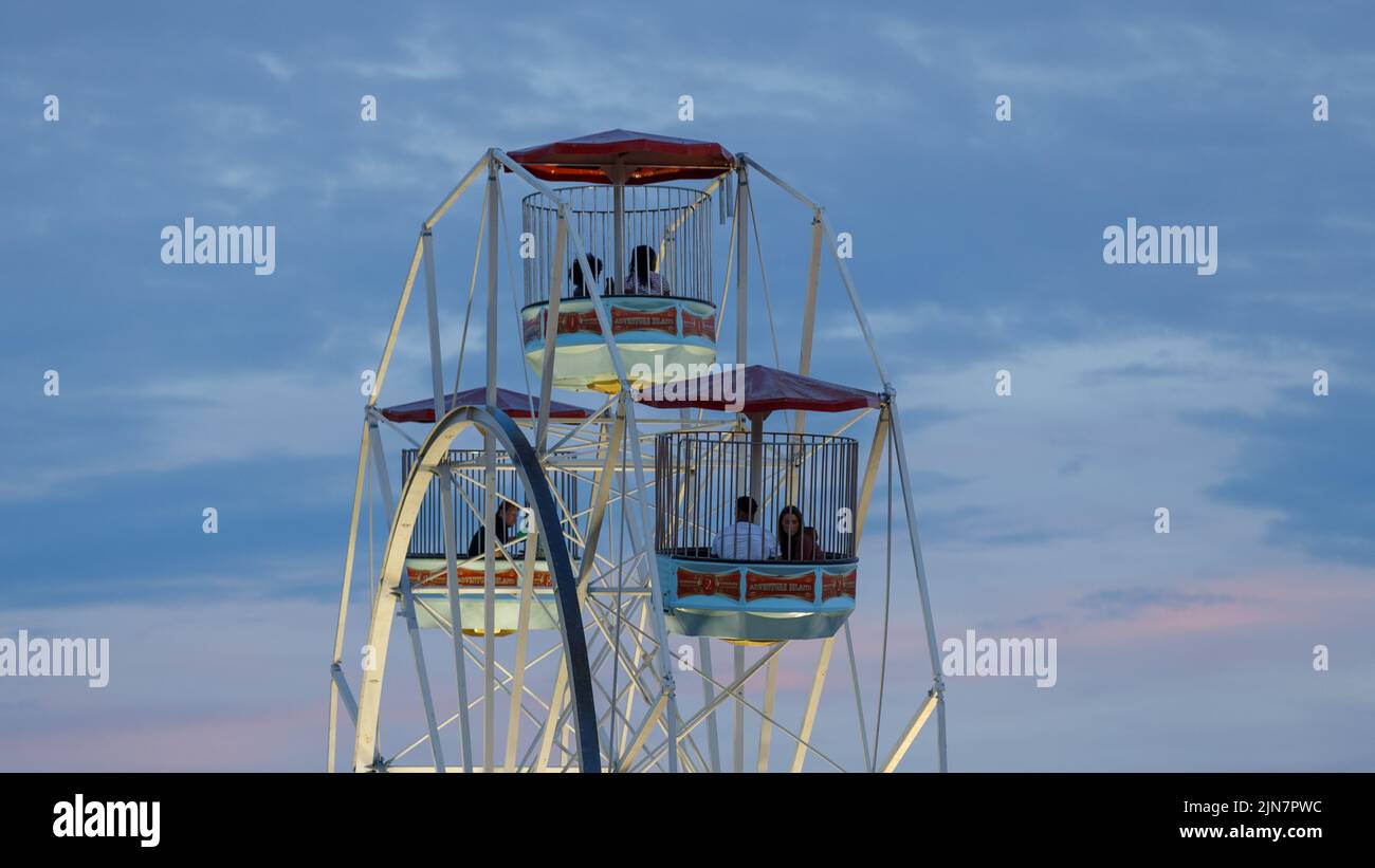 Paare sitzen in Riesenrad-Gondeln vor dem Sonnenuntergang Stockfoto