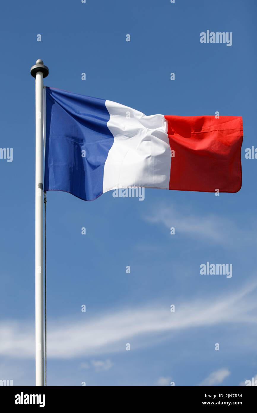 Französische Flagge flattert im Wind mit blauem Himmel Hintergrund. Tricolor auf einem weißen Fahnenmast Stockfoto