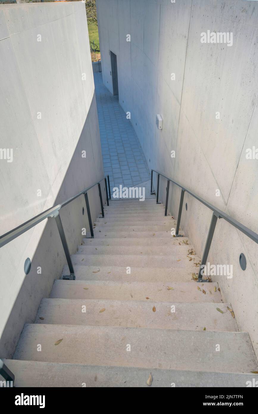 Treppe mit Metallgeländern, die zu einem Steinpflaster in Austin, Texas, führen. Treppe mit Betonstufen in der Mitte von Betonwänden. Stockfoto