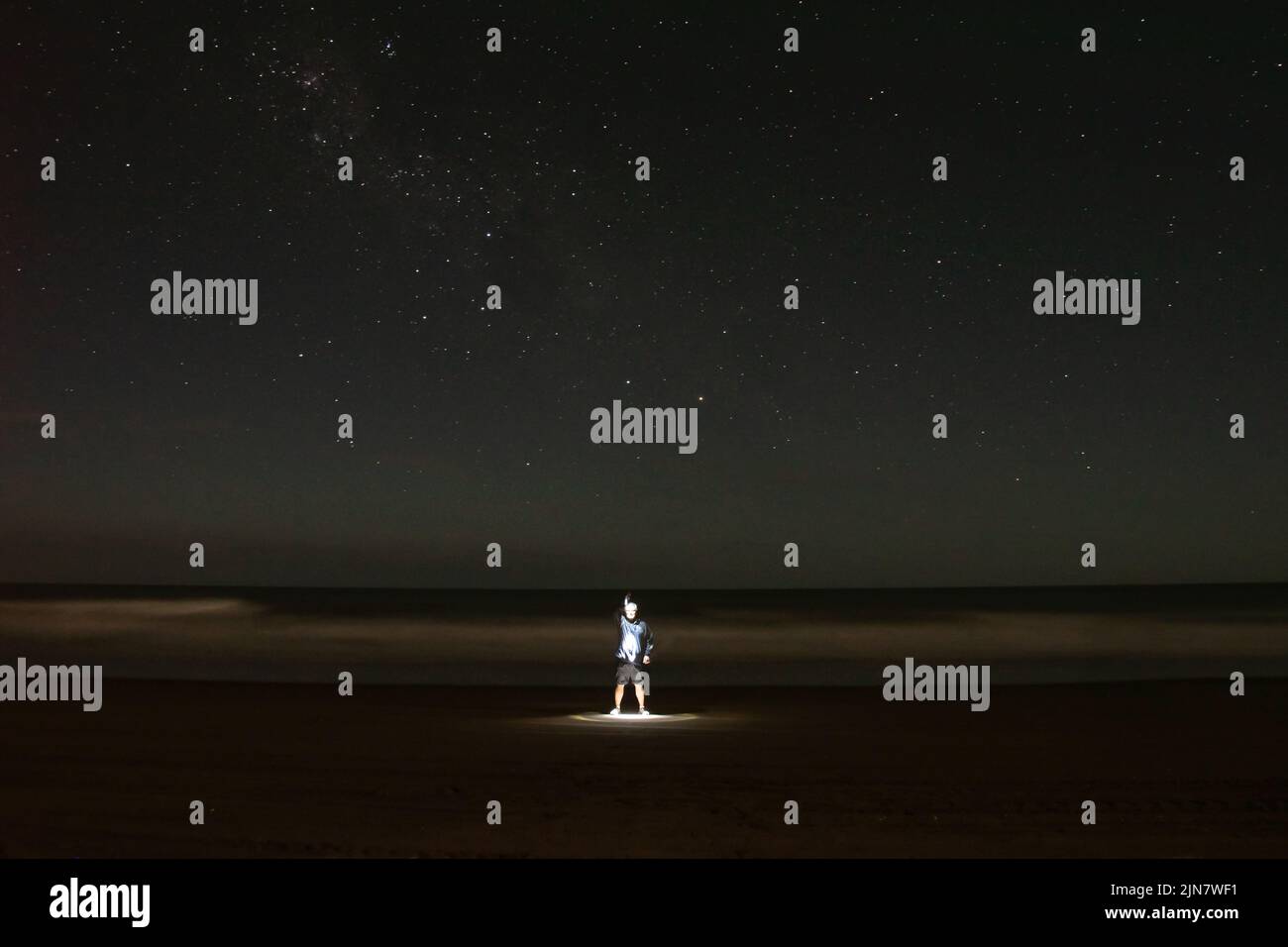 Nachtaufnahme eines beleuchteten Mannes am Meeresufer, Buenos Aires, Argentinien mit den Sternen Southern Cross am Himmel Stockfoto