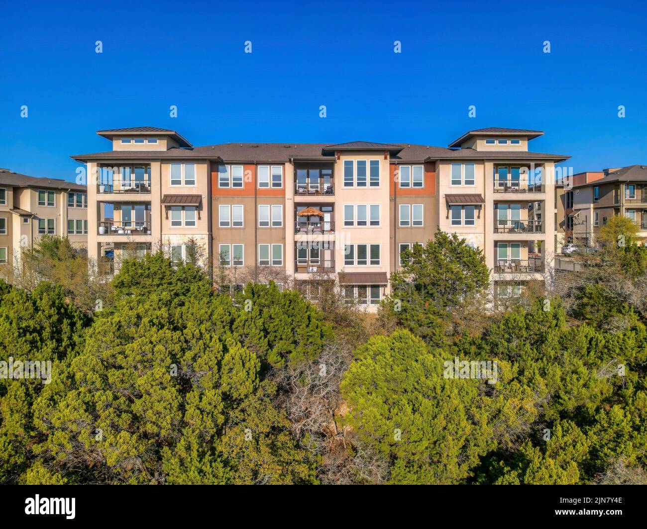 Austin, Texas- Apartmentgebäude mit Balkonen und Panoramafenstern auf einem Hang mit Bäumen Stockfoto