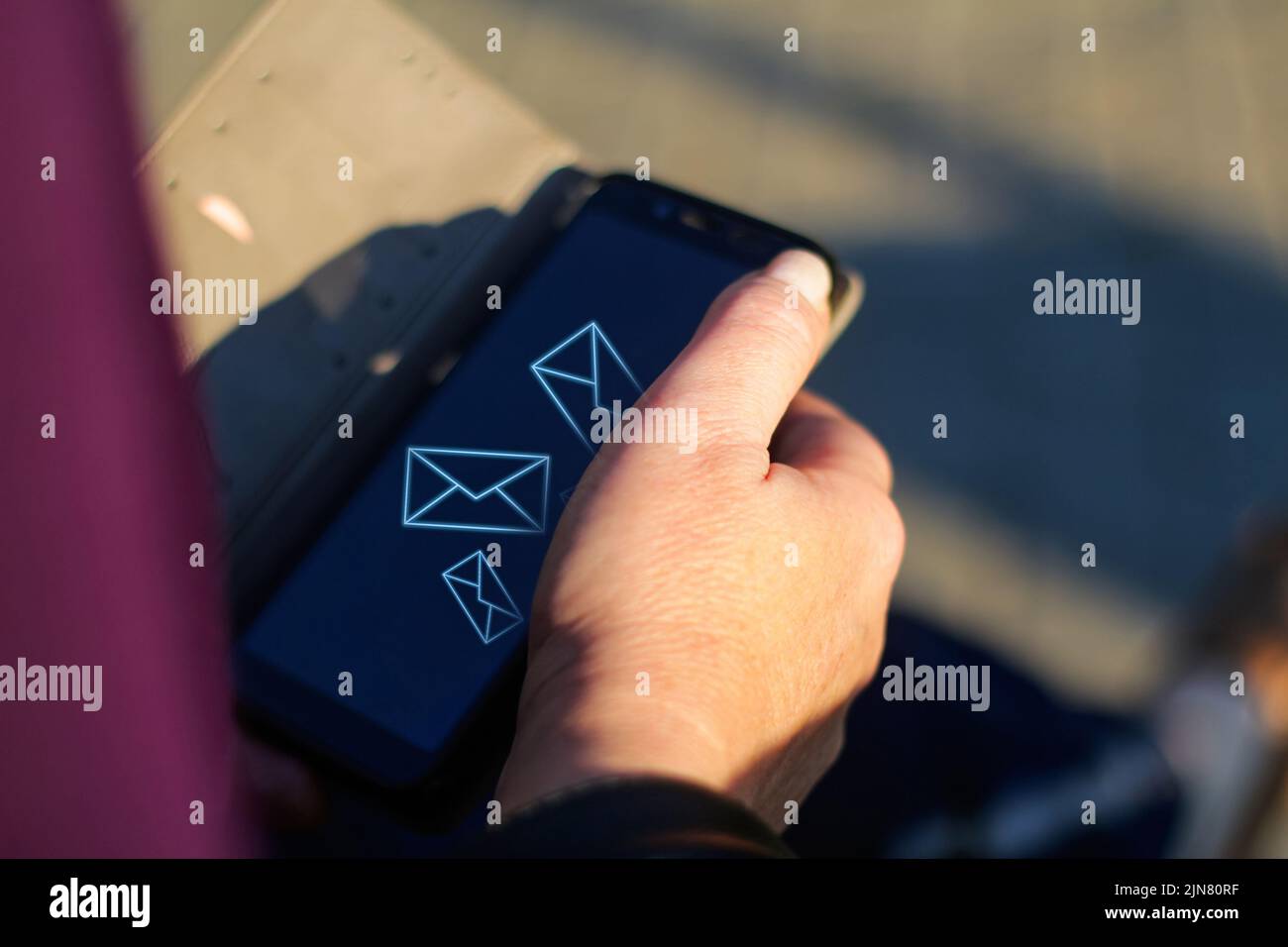 Unschärfe-Unschärfe-Nahaufnahme weibliche Hände suchen auf dem Telefon außerhalb, im Freien. Erwachsene Frau in lila Bluse mit Smartphone, während sie auf einer Bank in der p sitzen Stockfoto