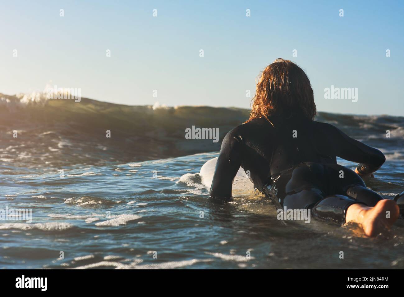 Das nenne ich die Gelegenheit. Rückansicht eines jungen Mannes, der im Meer surft. Stockfoto