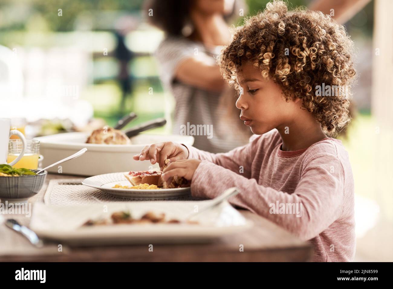 Hes immer bereit zu essen. Ein kleiner Junge, der sein Essen isst. Stockfoto