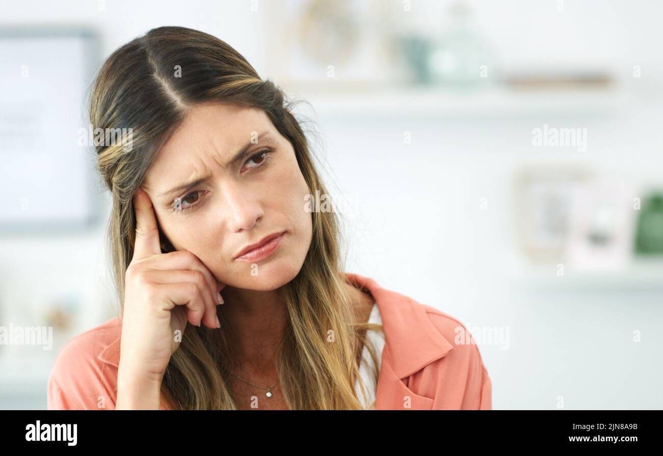 Ich fühle mich wirklich verwirrt... eine junge Frau, die aufgeregt aussieht, während sie zu Hause sitzt. Stockfoto