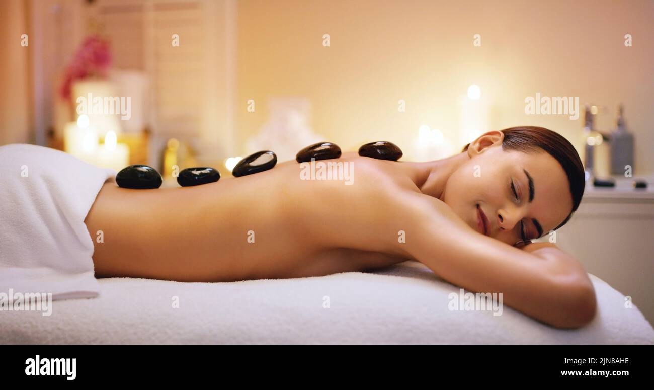 Spüren Sie das brennende Gefühl. Eine schöne junge Frau bekommt eine heiße Steinmassage in einem Beauty-Spa. Stockfoto