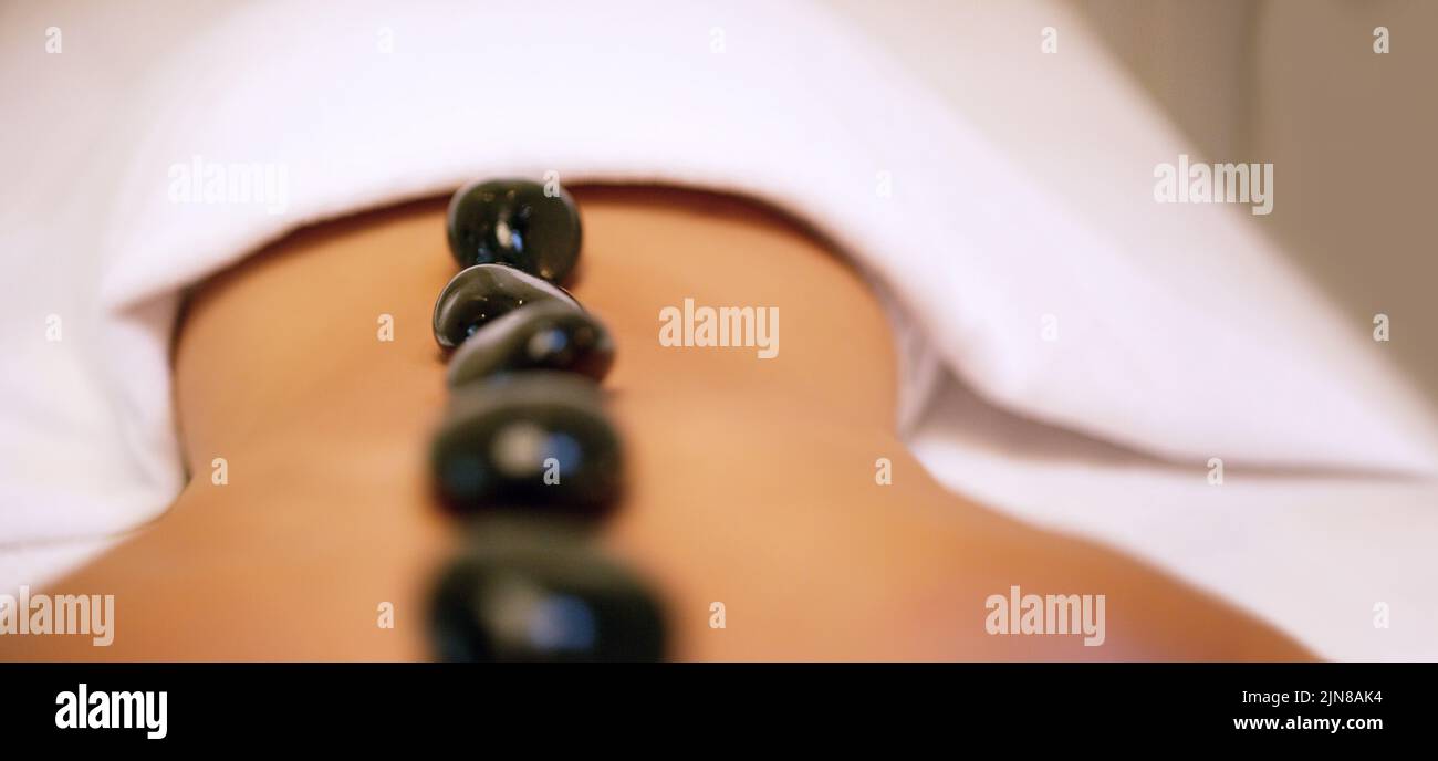 Stecken Sie in der Hitze des Augenblicks. Eine unkenntliche Frau bekommt eine Hot Stone Massage in einem Beauty Spa. Stockfoto