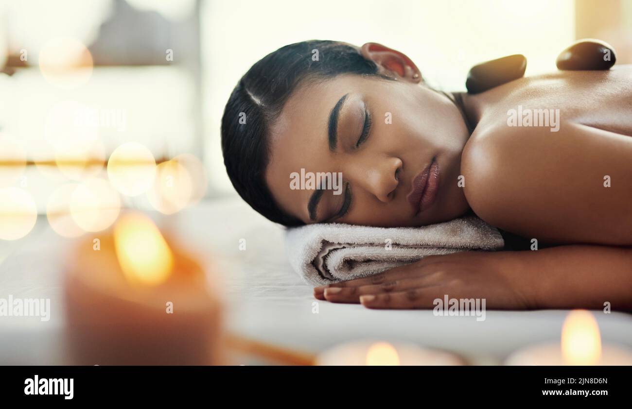 Ruhen Sie sich jetzt aus und genießen Sie das Erlebnis. Eine junge Frau bekommt eine Hot Stone Massage in einem Spa. Stockfoto