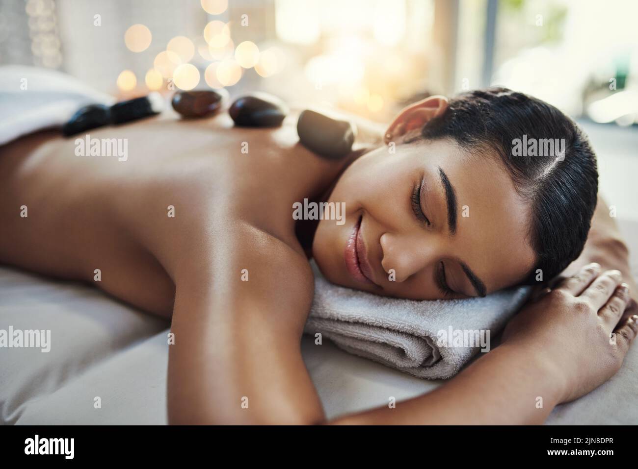 Eine junge Frau bekommt eine Hot Stone Massage in einem Spa. Stockfoto