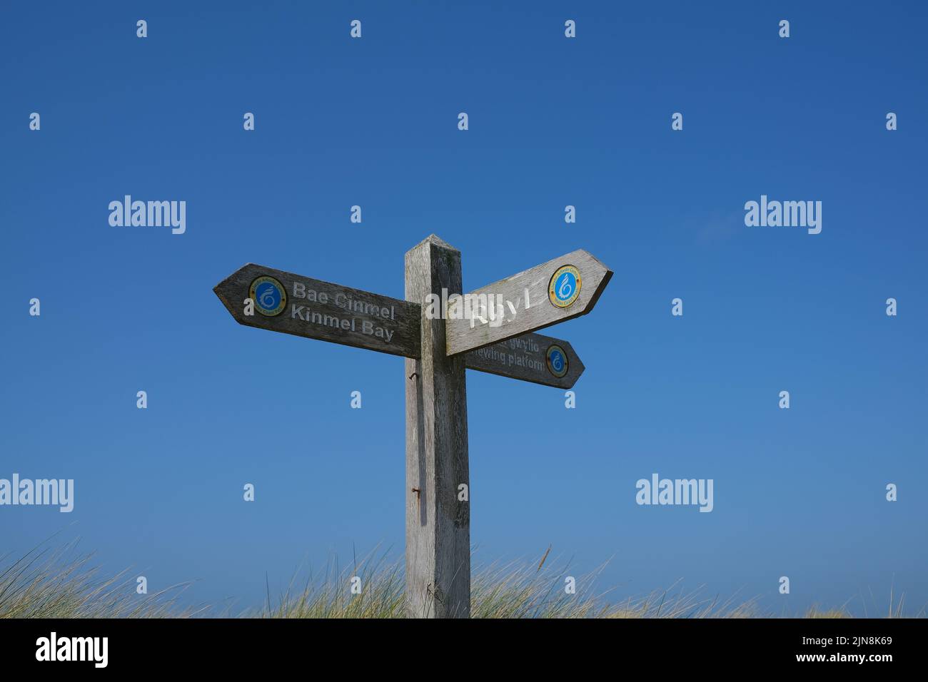 Ein Holzschild zeigt die Wegweiser nach Rhyl und BAE Cinmel Kinmel Bay Stockfoto