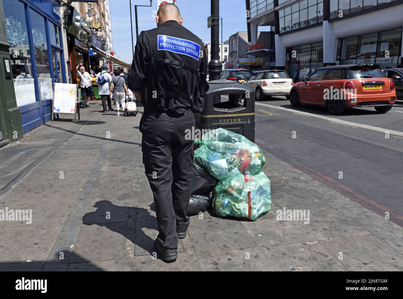 London, England, Großbritannien. Umweltschutzbeauftragter und ein Haufen Müll, der von einem Abfalleimer zurückgelassen wurde, Tooting Stockfoto