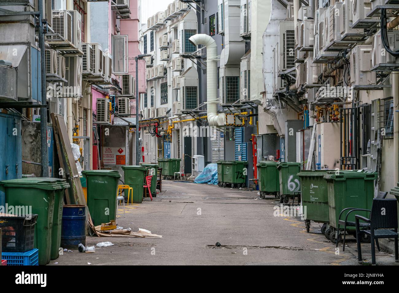 Die Fassade mit Reihen von Klimaanlagen und Müllcontainern ist in der Hintergasse am Boat Quay, Singapur, versteckt. Stockfoto