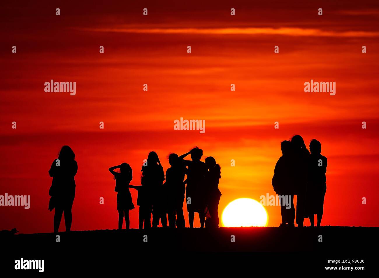 Gruppen von Menschen beobachten den Sonnenuntergang von einem Hügel in Ealing, West-London, während ein Sommer voller Rohrleitungsverbote und Feuerwarnungen anhält, wobei in weiten Teilen des Landes ein Wärmestandalarm ausgelöst wird. Bilddatum: Dienstag, 9. August 2022. Stockfoto