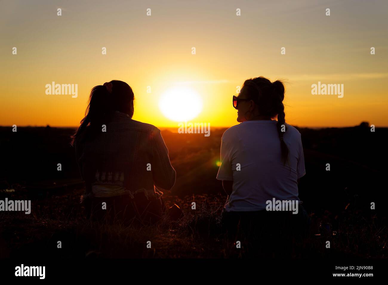 Zwei Frauen beobachten, wie die Sonne von einem Hügel in Ealing, West-London, untergeht, während ein Sommer voller Rohrleitungsverbote und Feuerwarnungen anhält, wobei in weiten Teilen des Landes ein Wärmestandalarm ausgelöst wird. Bilddatum: Dienstag, 9. August 2022. Stockfoto