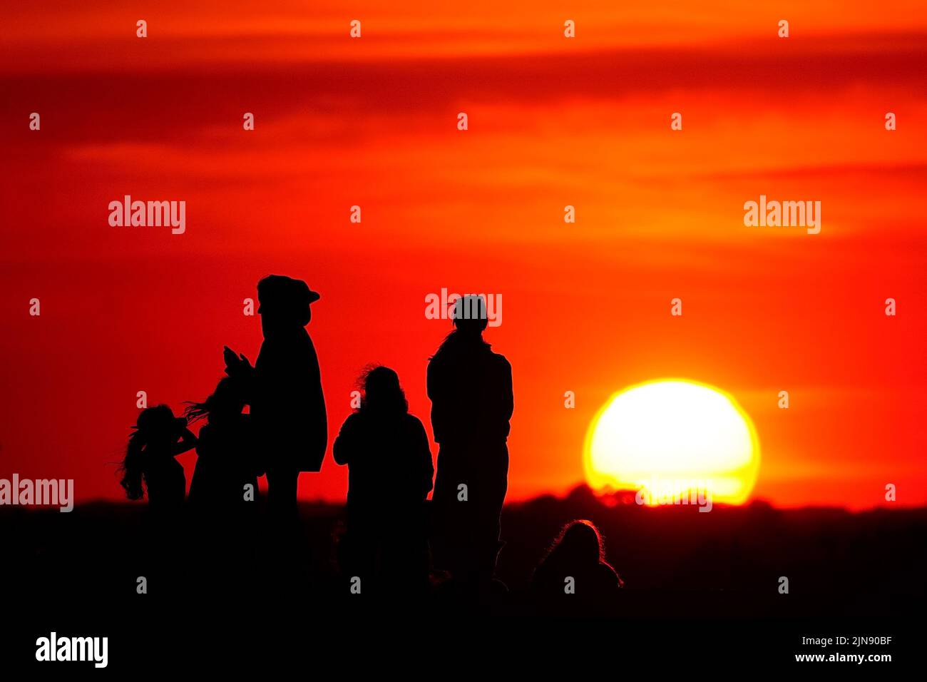 Gruppen von Menschen beobachten den Sonnenuntergang von einem Hügel in Ealing, West-London, während ein Sommer voller Rohrleitungsverbote und Feuerwarnungen anhält, wobei in weiten Teilen des Landes ein Wärmestandalarm ausgelöst wird. Bilddatum: Dienstag, 9. August 2022. Stockfoto