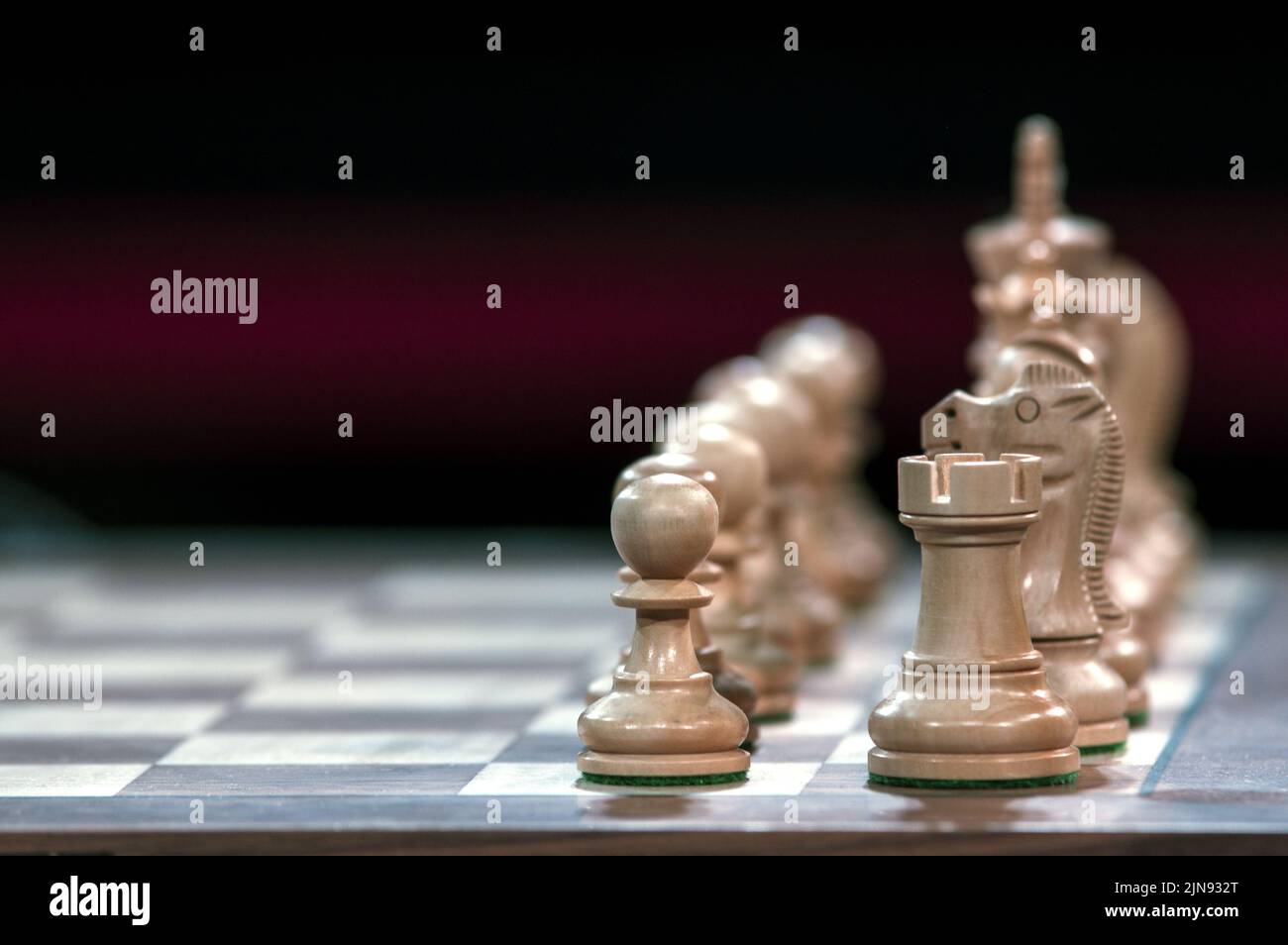 Nahaufnahme von Schachfiguren auf einem Schachbrett mit einem wunderschönen, verschwommenen Hintergrund. Rook, Ritter und Bauer im Vordergrund. Stockfoto