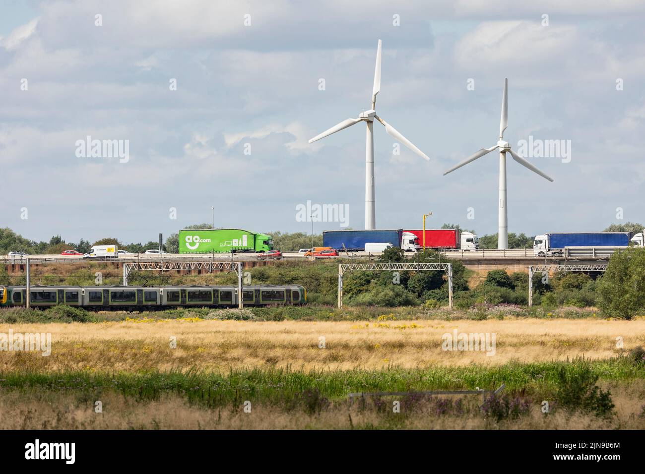 Stafford-Staffordshire-Vereinigtes Königreich 27. April 2022 grünes Sumpfland grenzt an eine verkehrsreiche Autobahn und Bahnlinie mit zwei Windenergieanlagen, Stockfoto