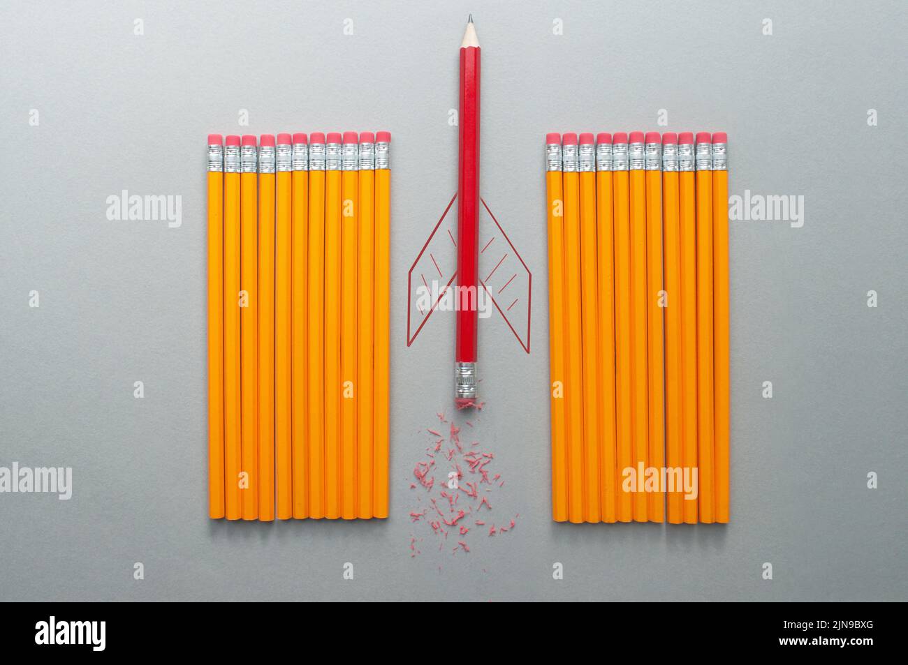 Roter Bleistift mit Raketenskizze, der sich zwischen einer Reihe orangefarbener Bleistifte heraussticht Stockfoto