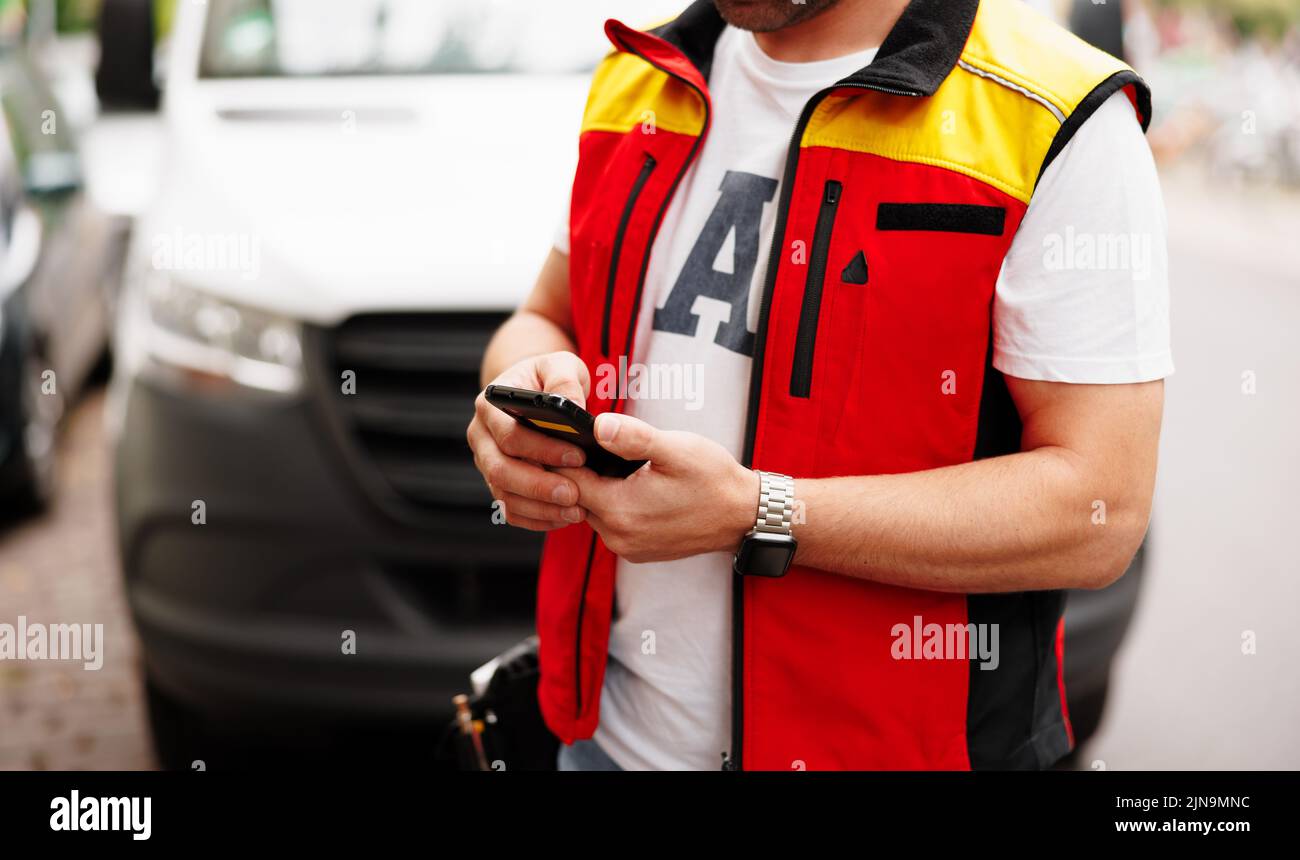 Zustelljunge, der mit dem Kunden auf dem Mobiltelefon spricht, während er nach einer Adresse sucht – Konzept für Kundenreaktion, Kommunikation nach Hause und Kurier Stockfoto