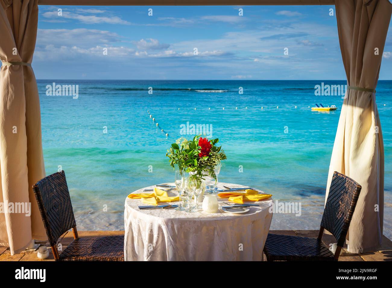 Romantischer Tisch für zwei Personen und Strand mit Pavillon bei Sonnenuntergang, Montego Bay, Jamaika Stockfoto