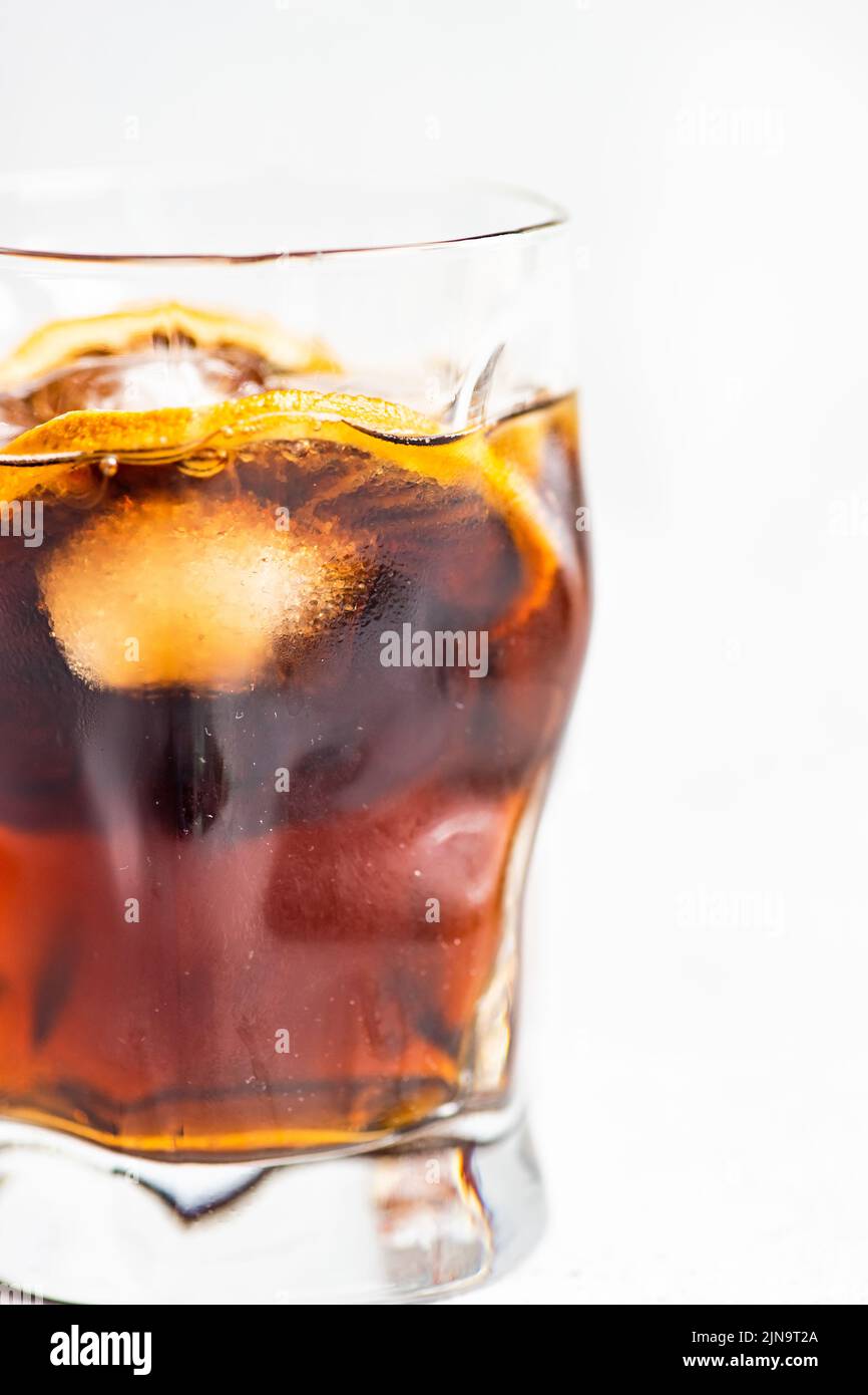 Alkoholcocktail mit Cola im Glas mit Orange und Eis auf grauem Betongrund Stockfoto