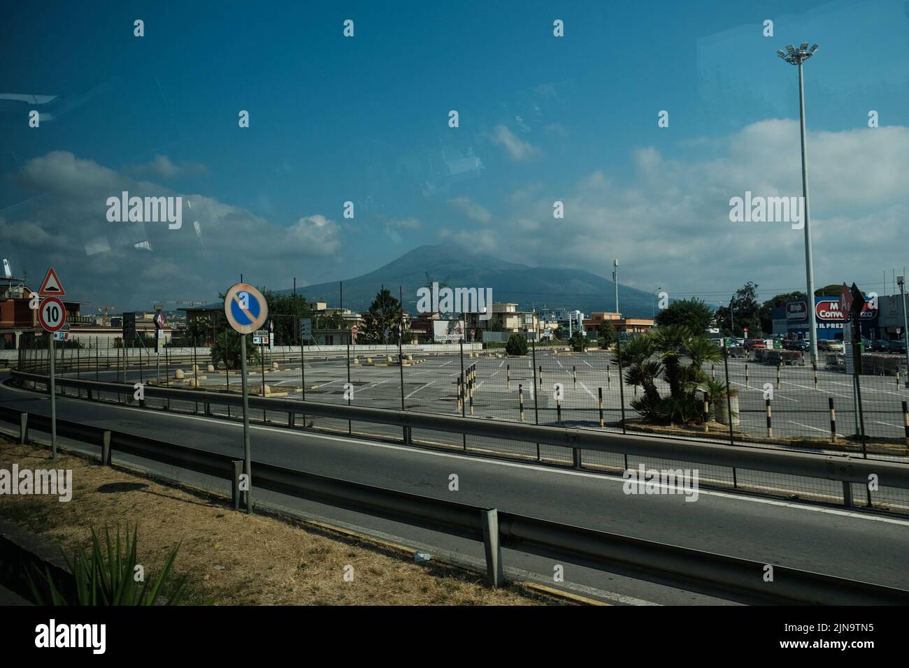 Blick auf den Vesuv mit Supermarkt-Parkplatz und Straße im Vordergrund. Als ruhender Vulkan sind Menschen, die unter dem Vulkan leben, gefährdet Stockfoto