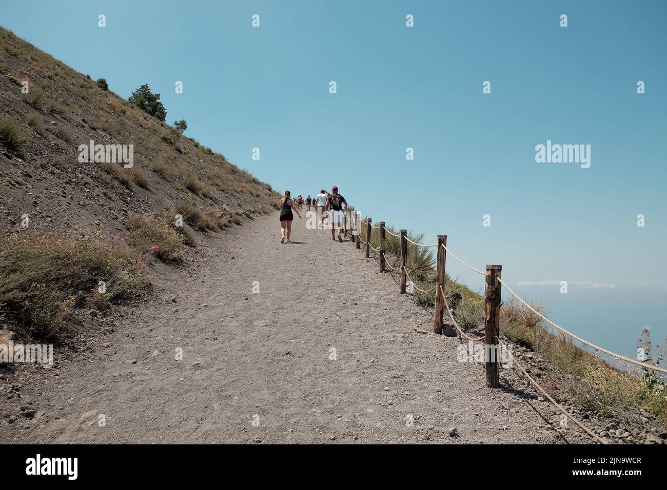 Touristen laufen den Beginn eines steilen Anstiegs auf den Gipfel des Vulkankegels des Vesuv im Golf von Neapel in Italien hinauf. Stockfoto