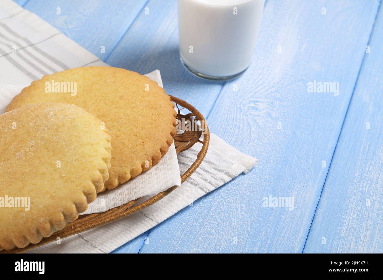 Lebkuchen mit gezackten Kanten enden Glas Milch auf blauem Holztisch Stockfoto