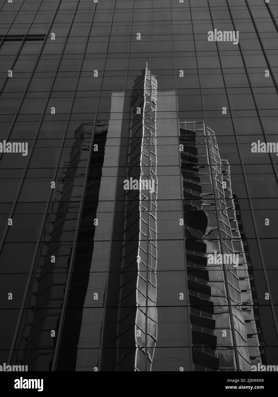 Ein Gebäudes spiegelt sich in der Fassade eines Hochhauses Stockfoto