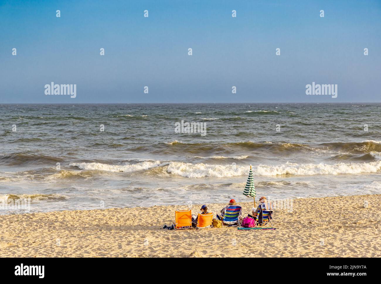 Drei Personen sitzen in Liegestühlen am Mecox Beach Stockfoto