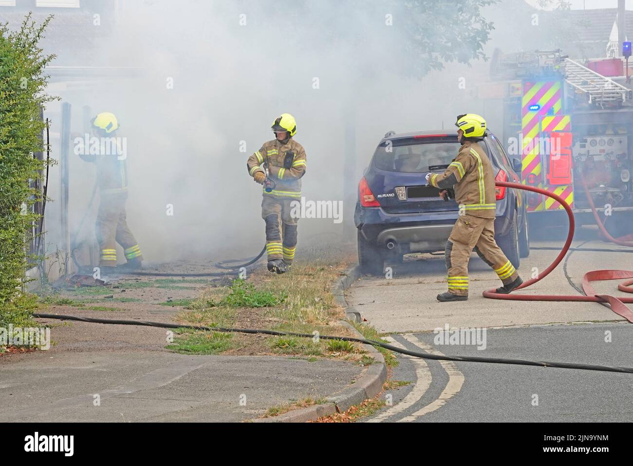 Essex Feuerwehr- und Rettungsdienst Team Arbeitsgruppe Feuerwehrleute in Schutzkleidung arbeiten in gefährlichen und gefährlichen Bedingungen auf Hausbrand England Großbritannien Stockfoto