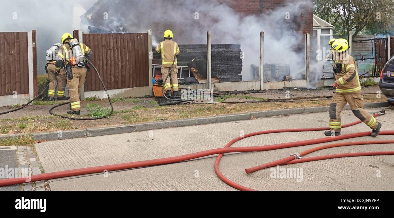 Essex Feuerwehr- und Rettungsdienst Feuerwehrleute in Schutzkleidung gefährliche und gefährliche Arbeiten am Hausbrand Arbeiten mit Atemschutzgeräten England Großbritannien Stockfoto