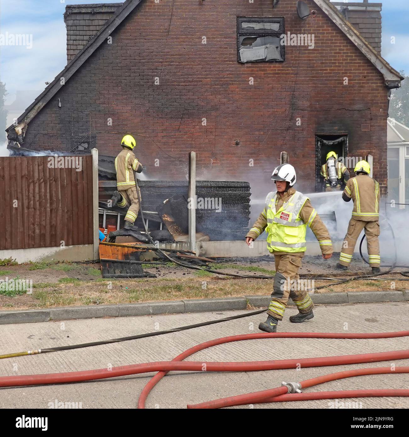 Essex Feuerwehr- und Rettungsdienst Feuerwehrmann in Schutzkleidung gefährliche & gefährliche Arbeit Innensuche Dämpfung nach Hausbrand England Großbritannien Stockfoto