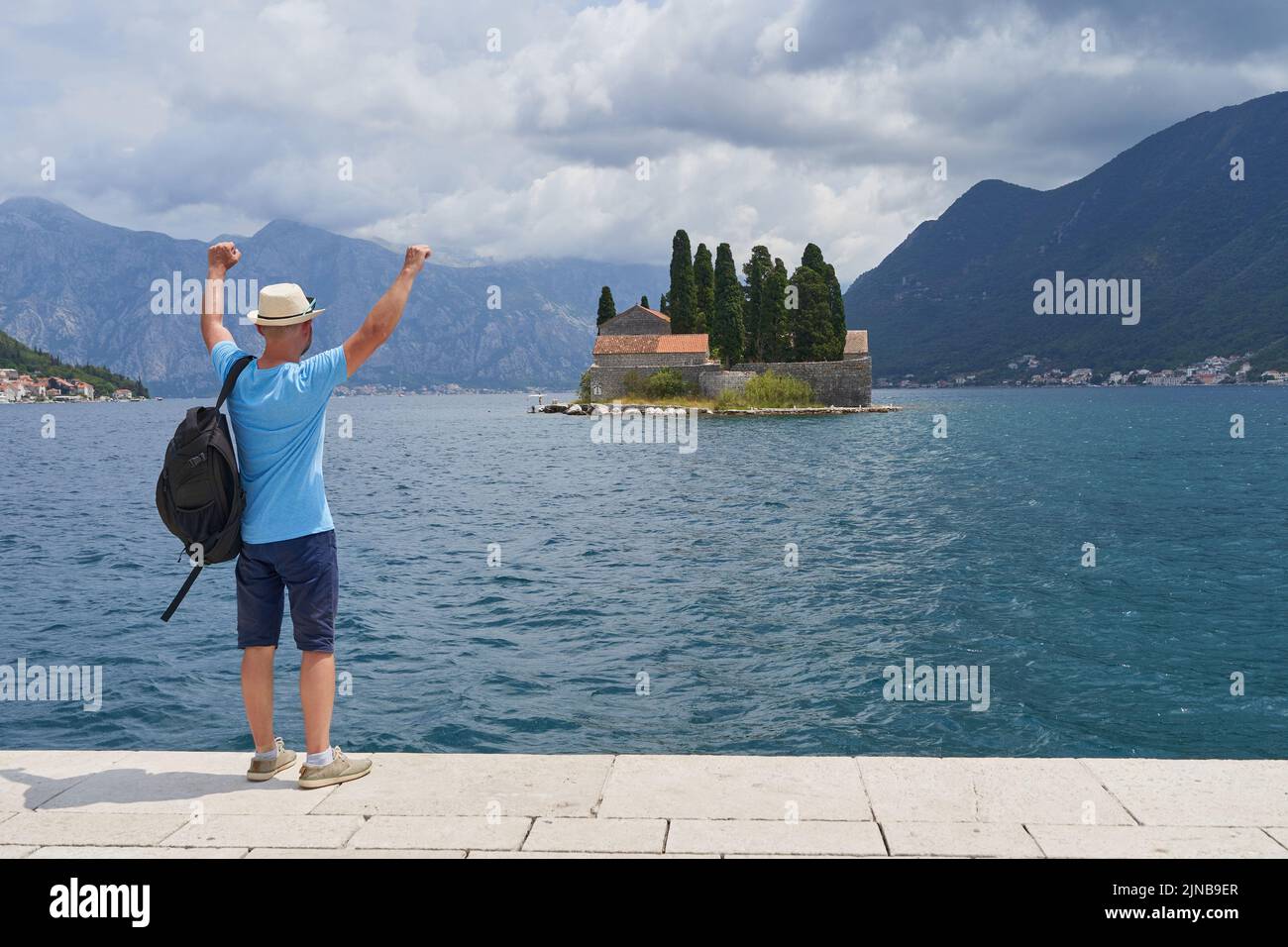 Männlicher Tourist blickt mit den Händen nach oben auf die Insel Stockfoto
