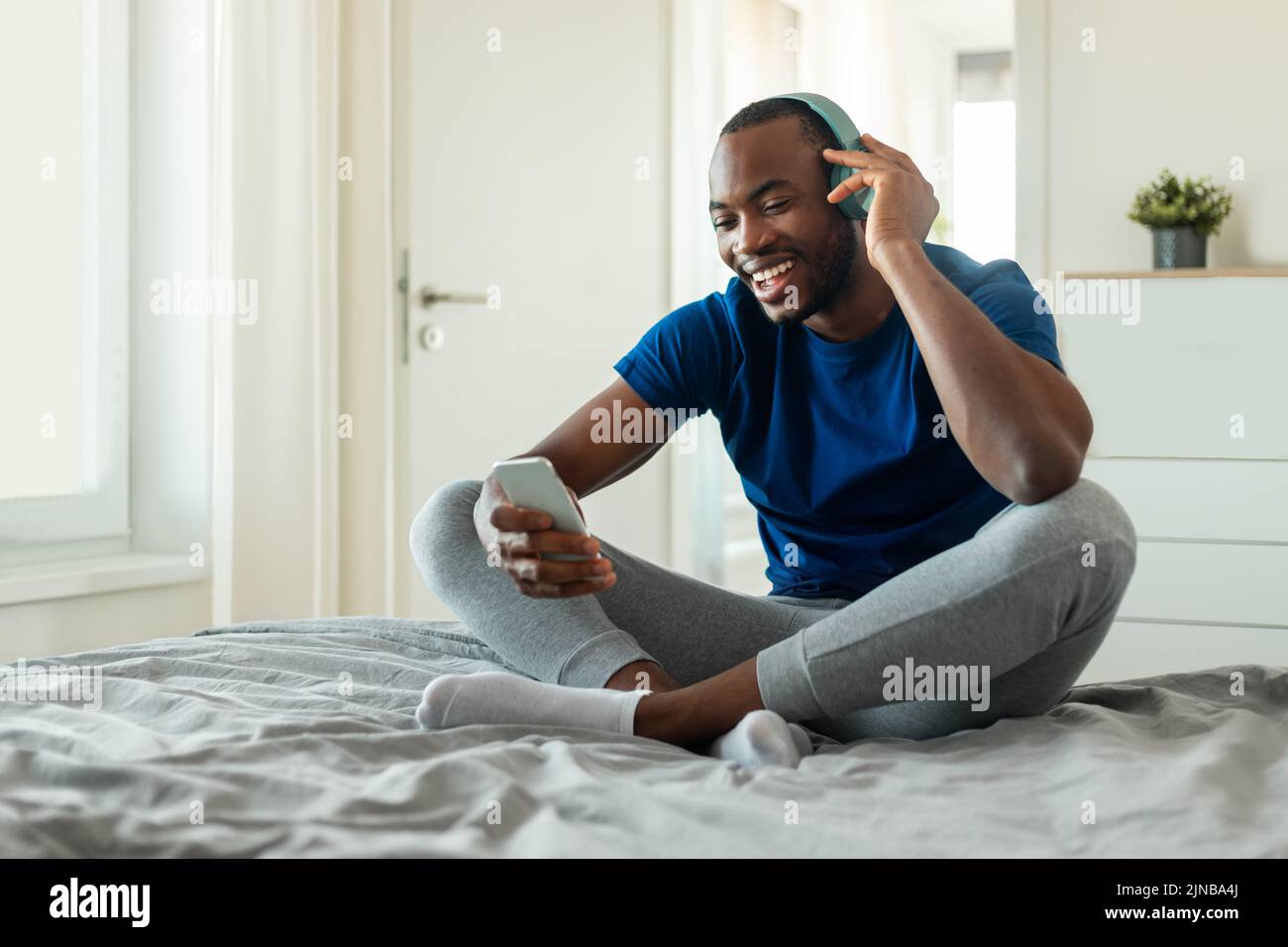 Afroamerikanischer Mann, Der Musik Lauschen Muss, Trägt Kopfhörer Im Schlafzimmer Stockfoto