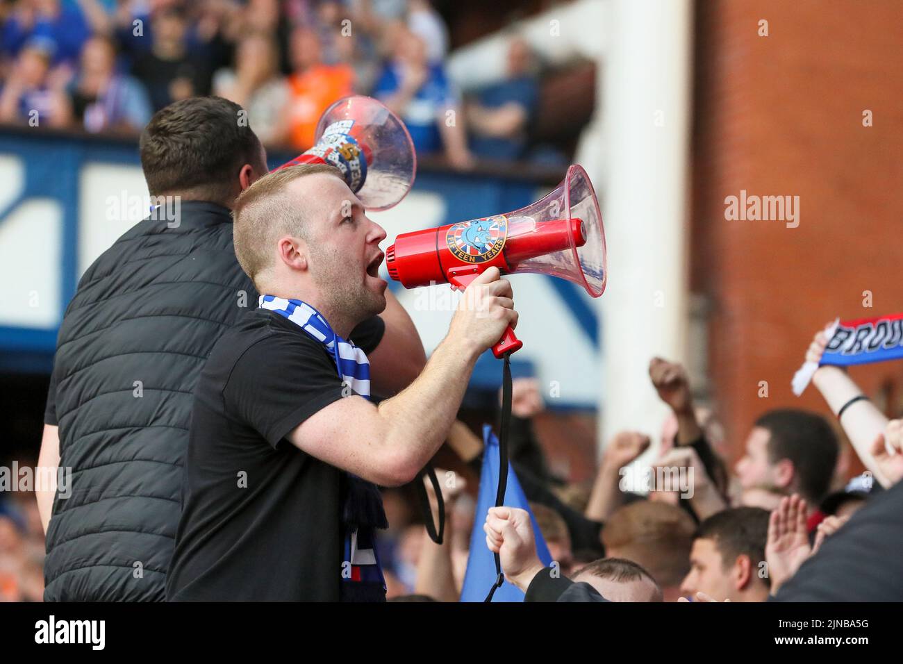 Ein Unterstützer des Fußballclubs Rangers FC, der das Chanten und Singen mit einem Lauthailer koordiniert, Ibrox Stadium, Glasgow, Großbritannien Stockfoto