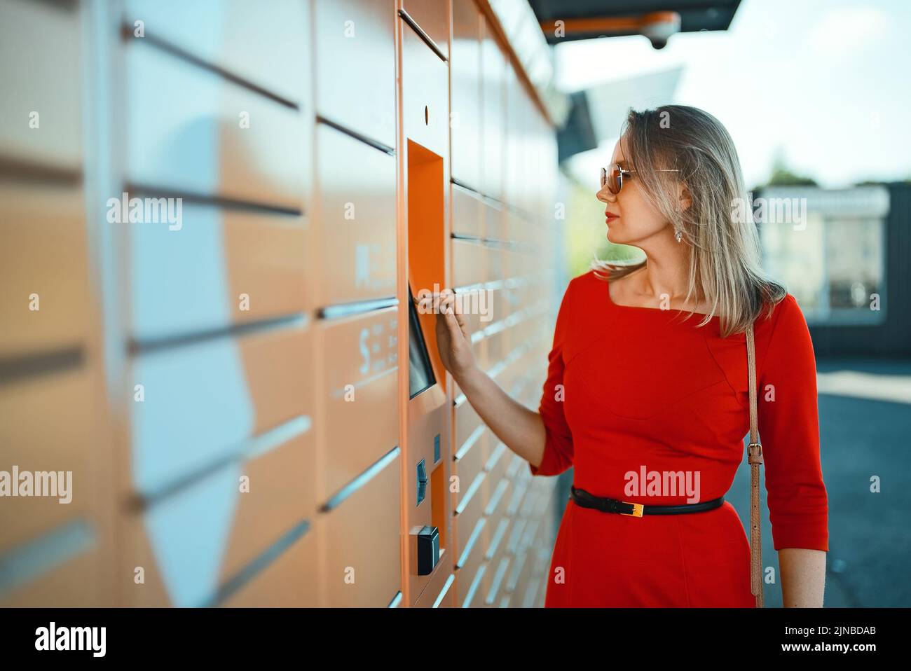 Frau holt Post vom automatischen Post-Terminal-Automaten ab. Stockfoto