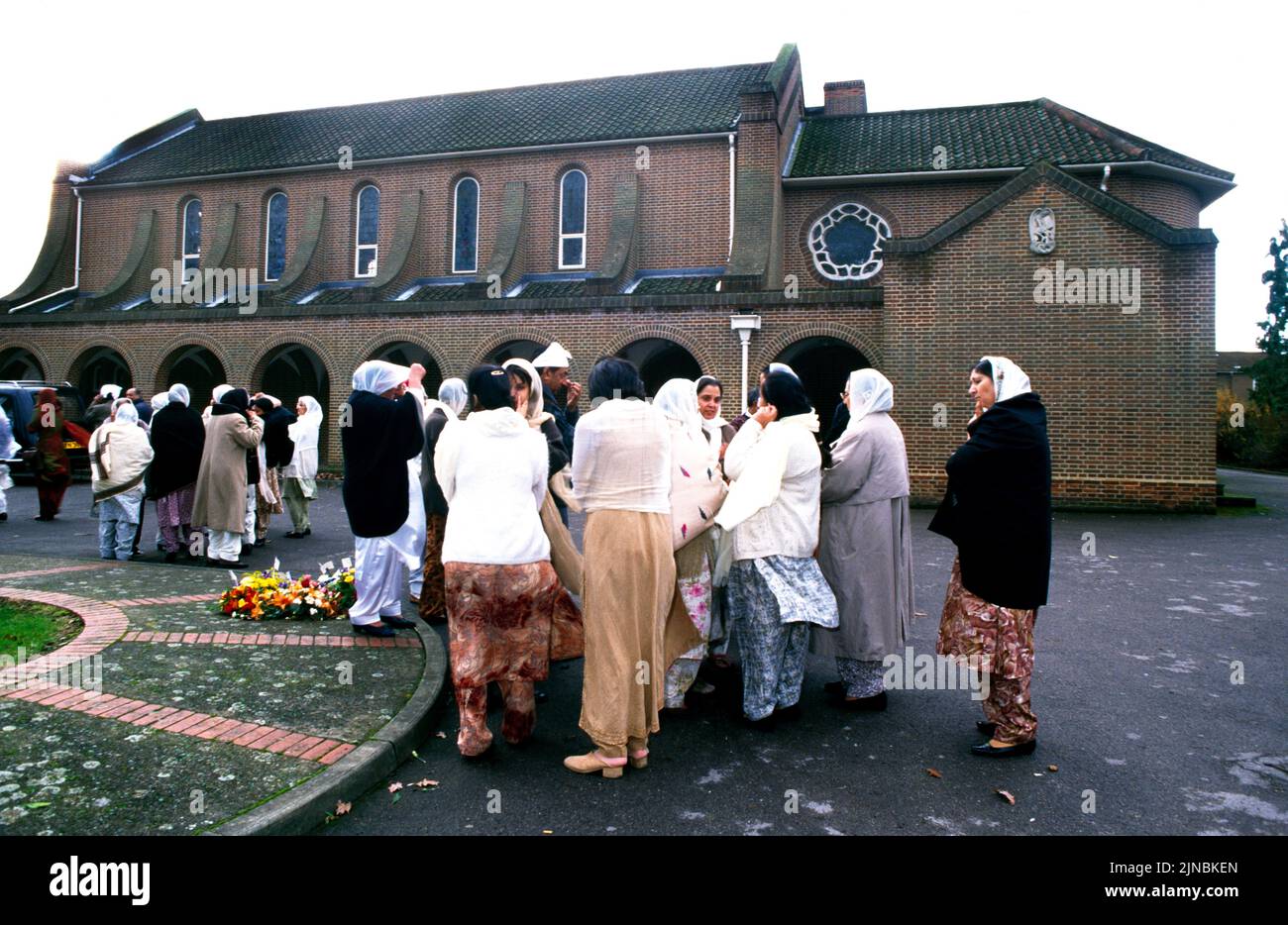 Sikh-Frauen bei Einem Begräbnis, das vor dem Krematorium wartet und auf Smoke Surrey England wartet Stockfoto