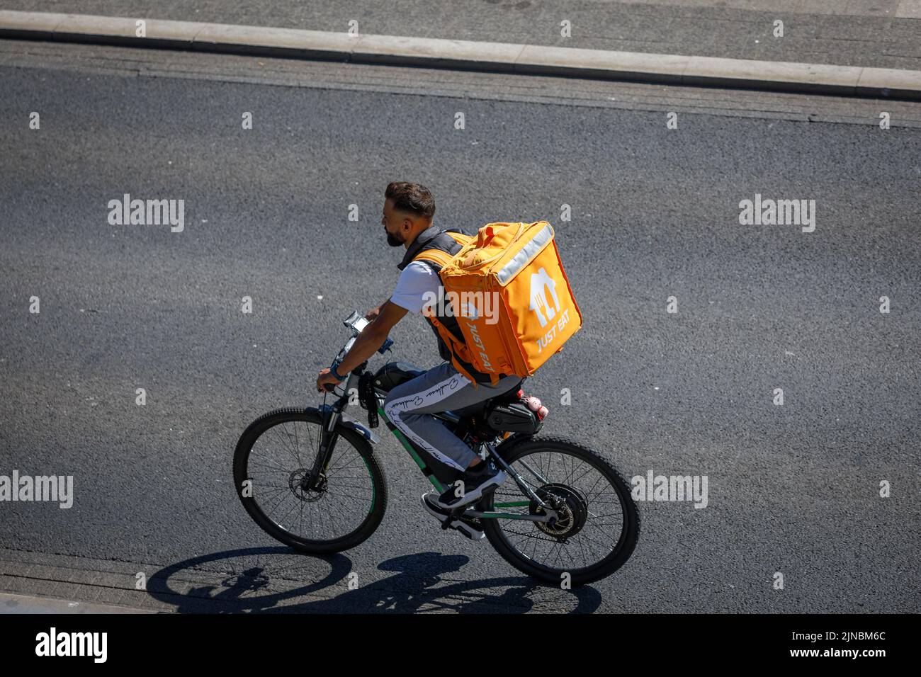 Essen Sie Einfach Die Lieferung. Essen Sie einfach Bike Delivery Rider mit großem orangenen Rucksack, radelt entlang einer Straße in England. Von oben aufgenommen Stockfoto