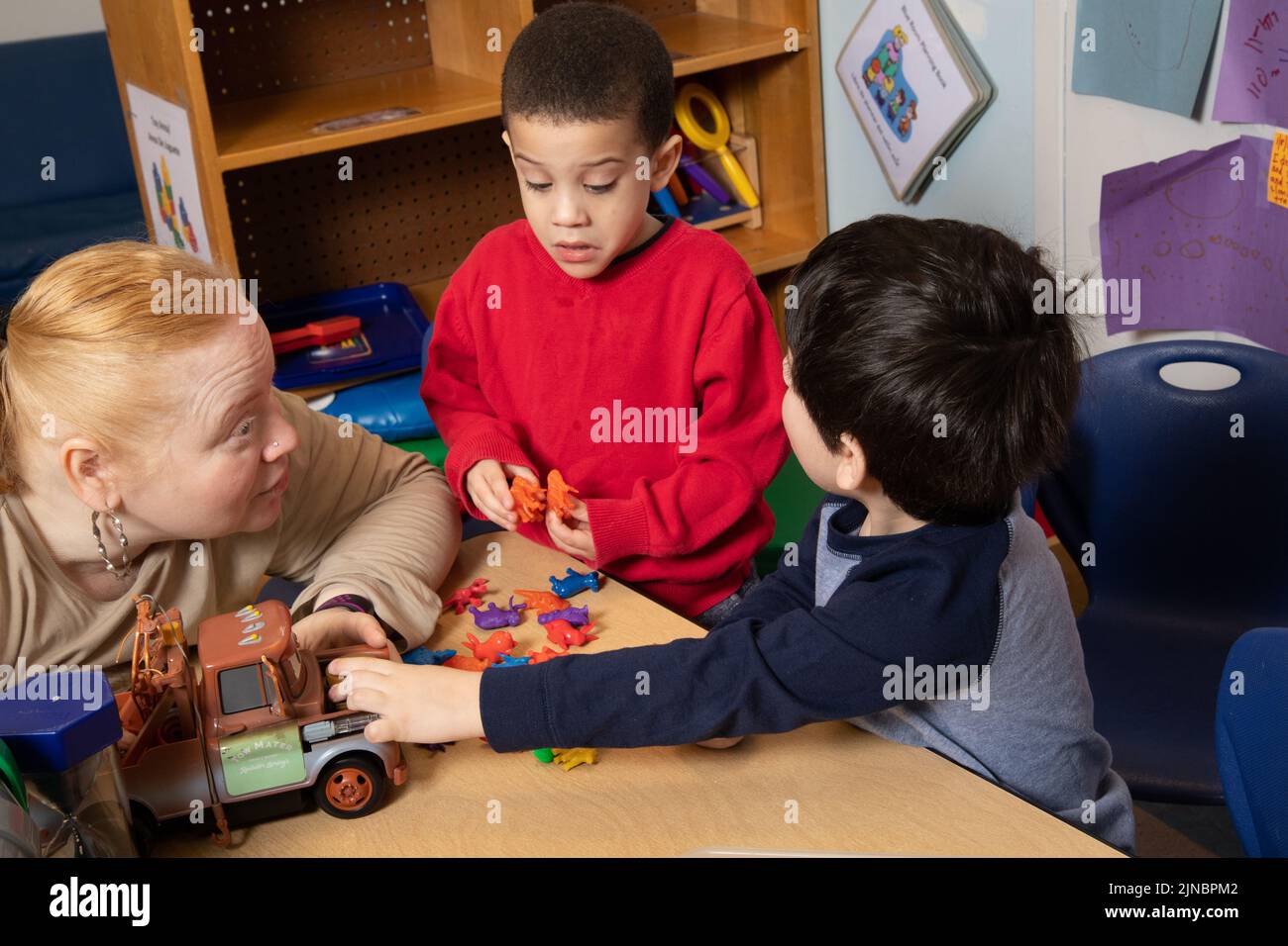 Bildung Vorschule Kinderbetreuung 3-Jährige zwei Jungen Streit um Spielzeug, Lehrer arbeitet mit Kindern, um Konflikte zu lösen, Lehrer hört zu restates pro Stockfoto