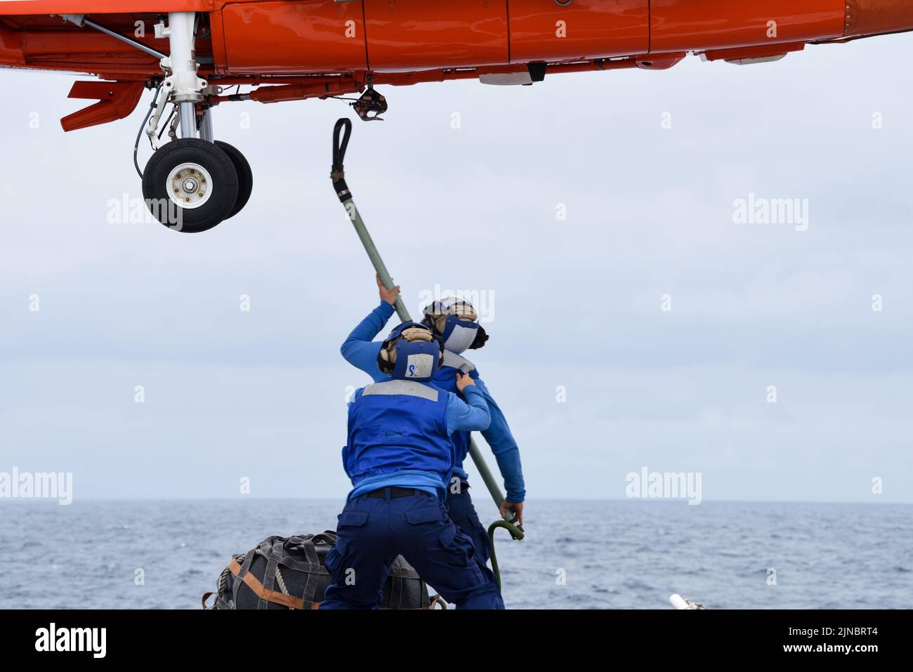 Die Crew der US-Küstenwache verbindet die Hebeschlinge während der Vertical Replenishment (VERTREP)-Einsätze mit der Coast Guard Air Station Houston MH-65 Dolphin-Hubschraubercrew an Bord des berühmten Mittelausdauerschneiders USCGC Mohawk (WMEC 913), der am 7. August 2022 im Atlantischen Ozean unterwegs ist. USCGC Mohawk ist im Einsatzgebiet der US Naval Forces Africa im Einsatz und wird von der Sechsten Flotte der USA eingesetzt, um die Interessen der USA, der Alliierten und der Partner zu verteidigen. (USA Foto der Küstenwache von Petty Officer, Klasse 3., Jessica Fontenette) Stockfoto