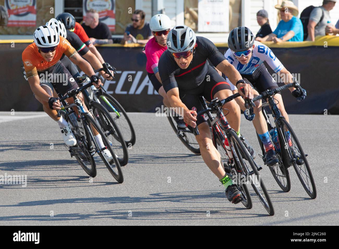 Radrennfahrer im Hauptfeld fahren eine Runde des Criterium, ein schnelles Radrennen, bei dem die Radfahrer auf den Straßen der Stadt mit ihren Rädern um einen Rundkurs fahren. Stockfoto