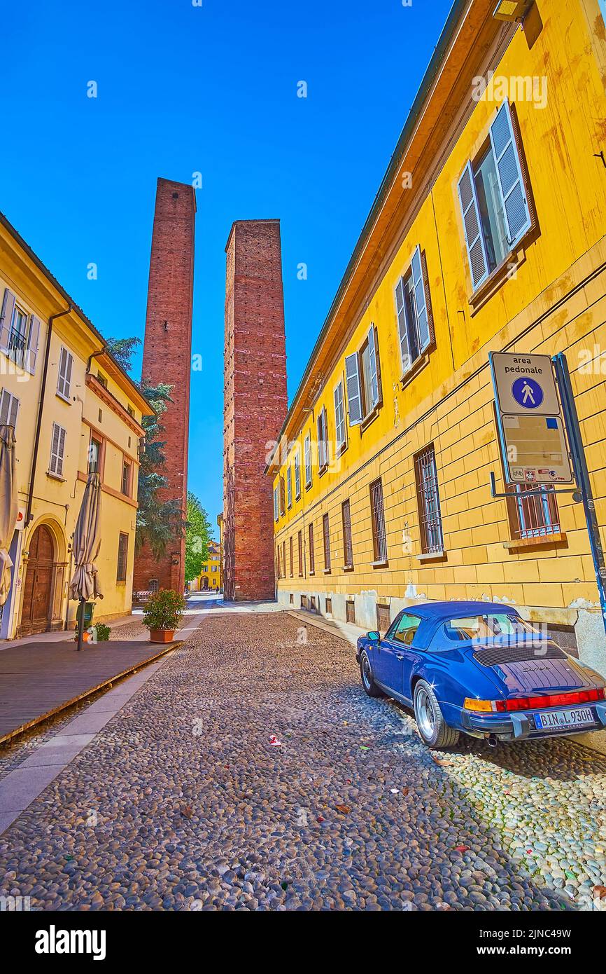 PAVIA, ITALIEN - 9. APRIL 2022: Spazieren Sie am 9. April in Pavia, Italien, entlang einer engen mittelalterlichen Straße zu den herausragenden Türmen auf der Piazza Leonardo da Vinci Stockfoto