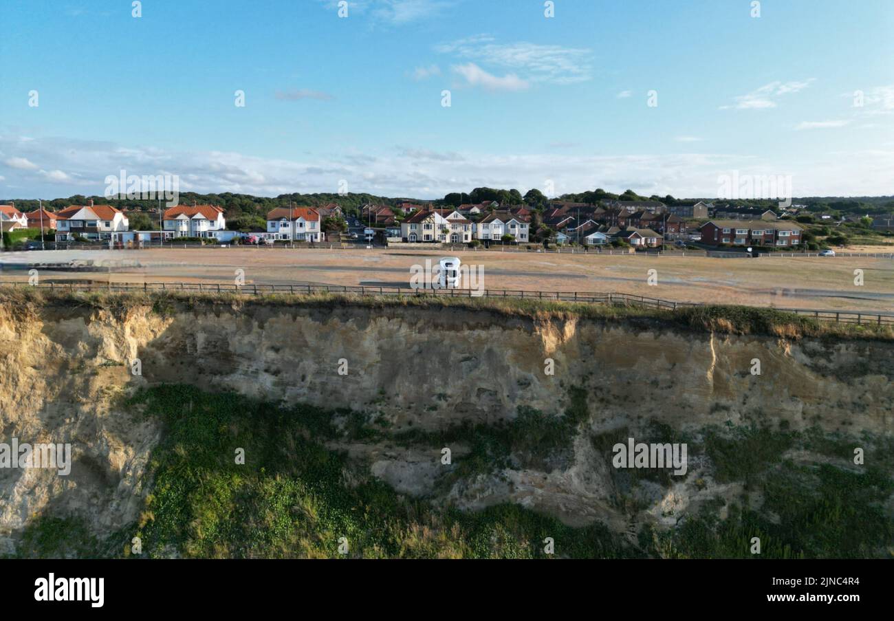 Ein Van parkte auf einer Klippe an einem Strand mit wunderschönen weißen Häusern im Hintergrund Stockfoto
