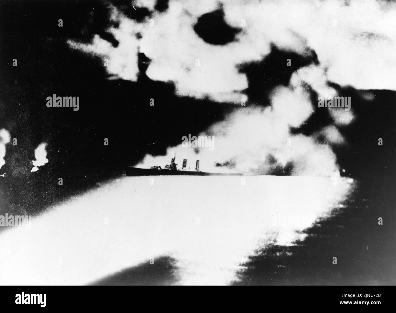 Ein dramatisches Foto des schweren US-Navy-Kreuzers USS Quincy (CA-39), fotografiert von einem japanischen Kreuzer während der Schlacht auf der Insel Savo, vor Guadalcanal, 9. August 1942. Quincy, hier brennend und von japanischen Suchscheinwerfern beleuchtet, wurde dabei versenkt. Stockfoto