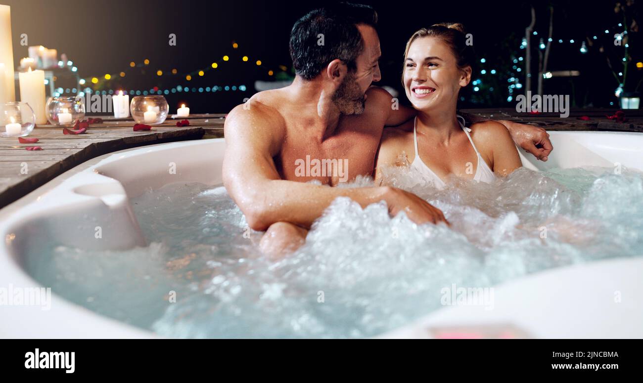 Wir feiern unseren Hochzeitstag mit Stil. Ein liebevolles reifes Paar, das sich nachts in einem Whirlpool entspannt. Stockfoto