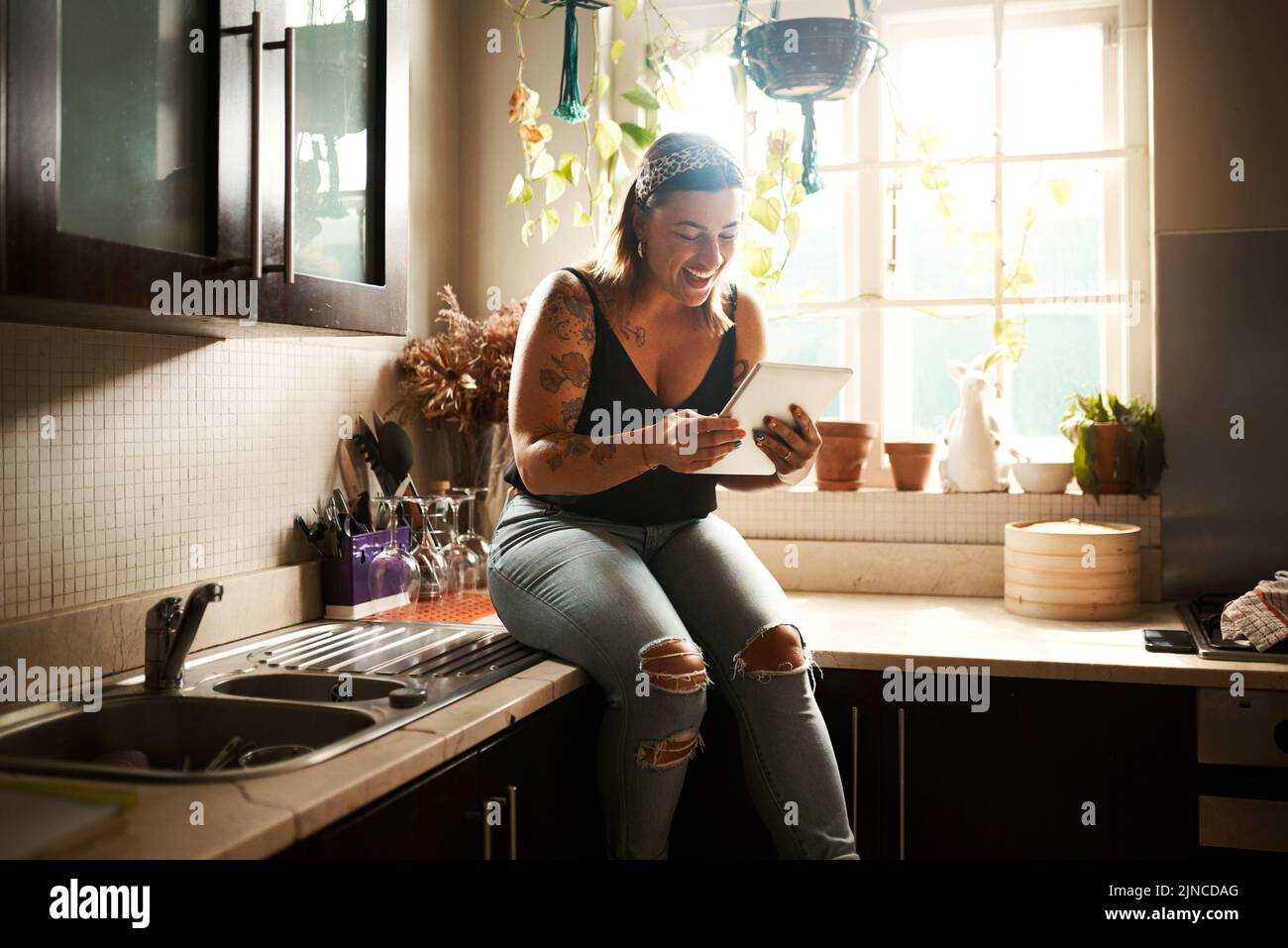 Surfen in sozialen Medien auf dem Tablet, Online-Suche und Lesen von lustigen Geschichten, Klatsch und Artikel über Technologie-App in der Küche zu Hause. Lächelnd und glücklich Stockfoto